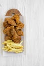 Fastfood: fried chicken legs, spicy wings, French fries and chicken strips over white wooden background, top view. Flat lay, Royalty Free Stock Photo