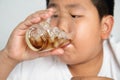 Fat Asian boy drinking soft drinks Wear a white shirt. Royalty Free Stock Photo