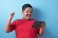 Fat Asian boy plays online game on his tablet gadget Royalty Free Stock Photo