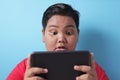 Fat Asian boy shocked when looking at his tablet