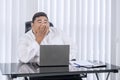 Fat Asian businessman feeling drowsy while working