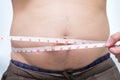 Fat asian man use waist measure for his belly Royalty Free Stock Photo