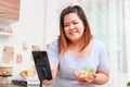 Fat Asian woman cooks organic food in her kitchen at home.