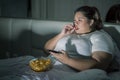 Fat Asian woman eating popcorns while watching TV Royalty Free Stock Photo