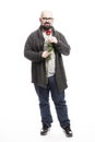 A fat bald man with glasses and a beard holds a red rose in his hands. Isolated over white background. Royalty Free Stock Photo