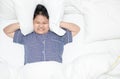 Fat boy covering head with pillow because too loud annoying noise Royalty Free Stock Photo