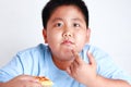 Fat boy eating bread The fingers point to the snack mouth. Royalty Free Stock Photo