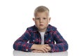 The fat boy is sitting at the table. Schoolboy in a plaid shirt. Back to school. Isolated on white background. Close-up Royalty Free Stock Photo