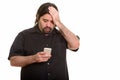 Fat Caucasian man looking tired while using mobile phone