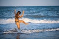 A girl with loose hair walks on the sea with waves and enjoys the sun Royalty Free Stock Photo