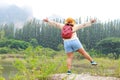 Fat female Asian tourist standing with arms and legs spread.