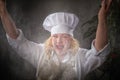 A fat funny female cook in a hat and apron posing and taking selfie in the kitchen with flour. Cooking, body positive Royalty Free Stock Photo