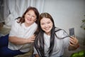 Fat funny funny adult mother and daughter posing, taking selfies indoors. Body positive, friendly family in room Royalty Free Stock Photo