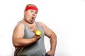 Fat funny man in red headband shows his muscles with dummbell and emotions Royalty Free Stock Photo