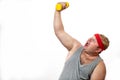 Fat funny man in red headband shows his muscles with dummbell and emotions Royalty Free Stock Photo