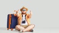 Fat funny man with a suitcase smiling on a gray background. Royalty Free Stock Photo