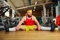 Fat funny man tired sitting on the floor in the gym Royalty Free Stock Photo