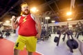 Fat funny man winner smiles in sports clothes in the gym. Royalty Free Stock Photo