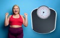 Fat girl does gym at home with satisfied expression because she decrease her weight. purple background
