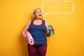 Fat girl does gym at home. satisfied expression. yellow background