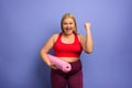 Fat girl does gym at home. satisfied and successfully expression. purple background. Royalty Free Stock Photo