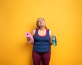 Fat girl does gym at home. tired expression. Yellow background