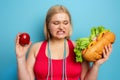 Fat girl does gym and want to eat a sandwich. Concept of indecision and doubt Royalty Free Stock Photo