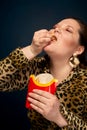 Fat girl eating french fries from a glass. The concept of gluttony.