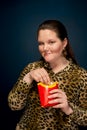 Fat girl eating french fries from a glass. The concept of gluttony.