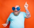 Fat happy man with beard, tattoos and sunglasses dances music