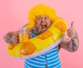 Fat happy man with wig in head is ready to swim with a donut lifesaver