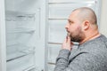 Fat hungry man is looking for a food into empty fridge Royalty Free Stock Photo