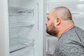 Fat hungry man is looking for a food into empty fridge Royalty Free Stock Photo