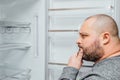 Fat hungry man is looking for a food into empty fridge Royalty Free Stock Photo