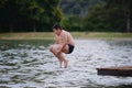 Active fat little boy jumping into water of summer lake in outdoor leisure green plant park Royalty Free Stock Photo