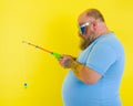 Fat man with beard and sunglasses is unhappy with the fishing rod