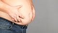 Fat man, checking his weight, on a gray background Royalty Free Stock Photo