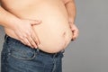 Fat man, checking his weight, on a gray background Royalty Free Stock Photo