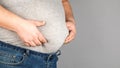 Fat man, checking his weight, on a gray background Royalty Free Stock Photo