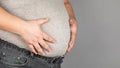 Fat man, checking his weight, on a gray background Royalty Free Stock Photo