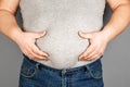 Fat man, checking his weight, on a gray background Royalty Free Stock Photo