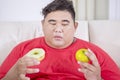 Fat man confused between prefer doughnut or apple Royalty Free Stock Photo