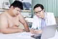 Fat man and doctor looking at medical result