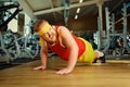 A fat man does push-ups from the floor in the gym.