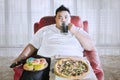 Fat man drinking a glass of cola on the sofa Royalty Free Stock Photo