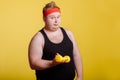 Fat man with dumbbell on yellow background. Motivation for fat people Royalty Free Stock Photo