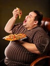 Fat man eating fast food slice pizza. Breakfast for overweight person.