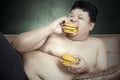 Fat man eating two hamburgers Royalty Free Stock Photo