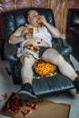 Fat man eating and watching television Royalty Free Stock Photo