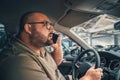 Fat man in glasses talking on cell phone while driving car in parking lot Royalty Free Stock Photo